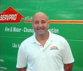 Michael Panster Owner of the SERVPRO of Pompano Beach franchise smiling in front of a green SERVPRO vehicle.
